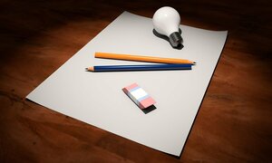 Glödlampa, penna och radergummi som ligger på ett pappersark. Bild.